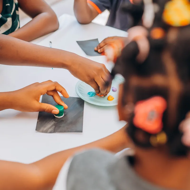 Children's hands busy with an art project around a shared table